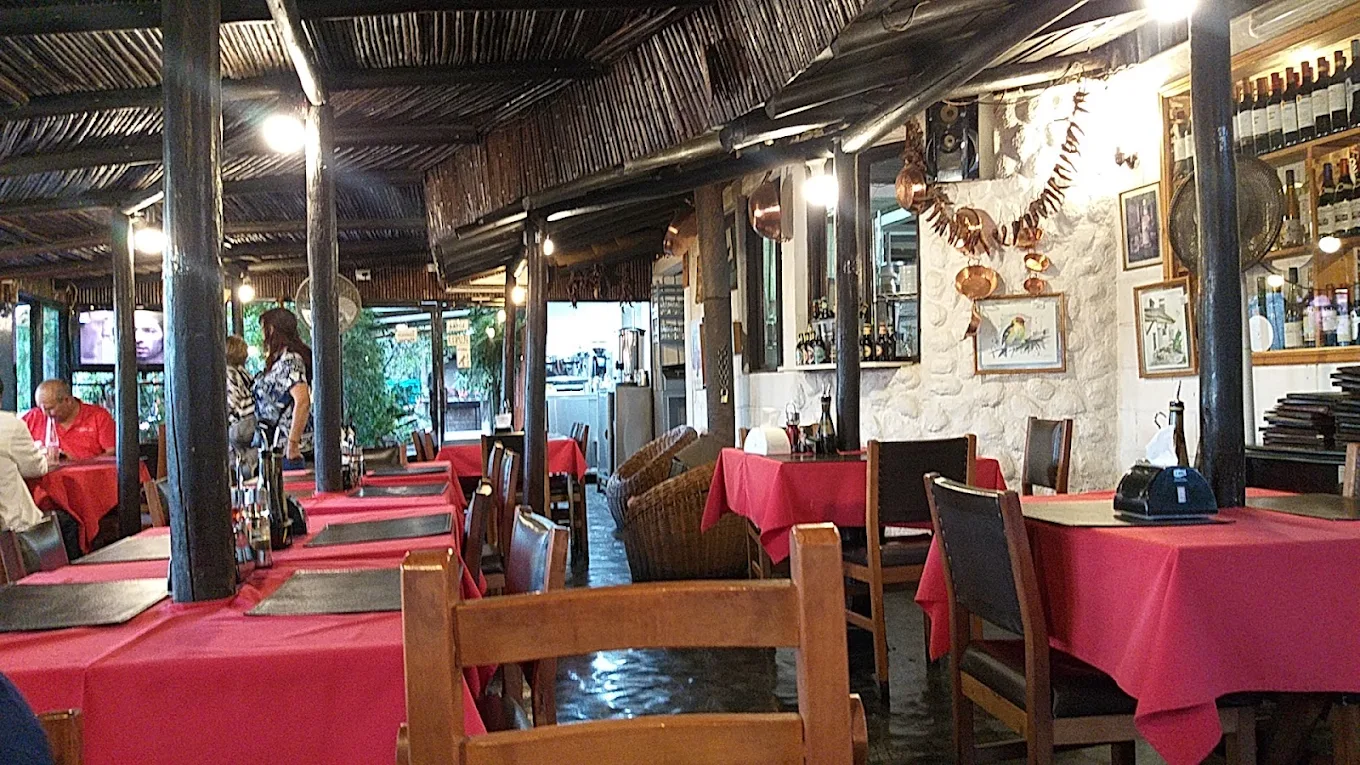 Comedor del Restaurant El Quillay, con vigas de madera y mesas con mantel rojo