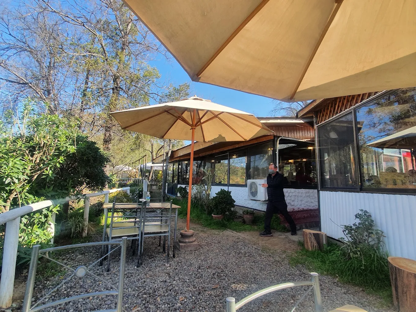 Terraza del Restaurant El Quillay, con mesas bajo sombrillas entre los árboles
