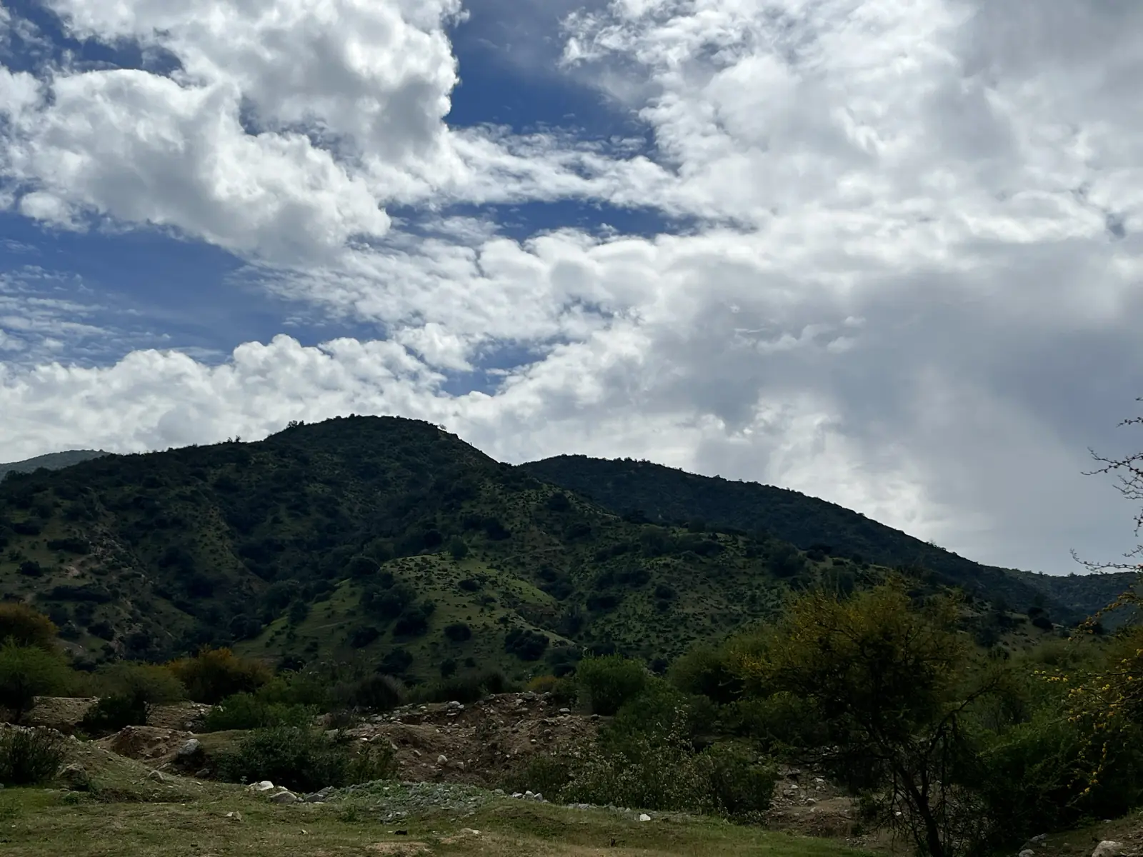 Cerros verdes bajo un cielo con nubes, vistos desde la poza