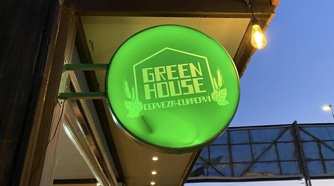 Letrero luminoso verde de Green House, cerveza de Curacaví, colgado en la fachada